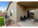Inviting covered back patio area featuring patio chairs and access to the home's interior at 42370 W Hillman Dr, Maricopa, AZ 85138