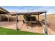 Covered gazebo with table and chairs on a brick patio in a well-manicured backyard at 42370 W Hillman Dr, Maricopa, AZ 85138