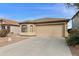 Tan single-story home featuring a two-car garage and xeriscaped front yard at 42370 W Hillman Dr, Maricopa, AZ 85138