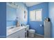 Well-lit bathroom with blue walls featuring a sink, toilet, vanity and decorative hanging light at 4332 E Calle Redonda St, Phoenix, AZ 85018
