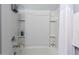 Bathroom tub and shower with white tile, shower curtain, and built-in shelving at 45975 W Mountain View Rd, Maricopa, AZ 85139