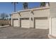 Three-car garage with white doors and modern sconces, complemented by desert landscaping under a clear blue sky at 4927 E Hazel Dr # 2, Phoenix, AZ 85044