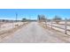 Long, gravel driveway is framed by white fencing, leading to the charming property at 49853 W Jean Dr, Maricopa, AZ 85139
