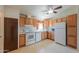 Bright kitchen featuring oak cabinets, white appliances, and tile floor at 49853 W Jean Dr, Maricopa, AZ 85139