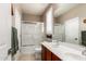 Clean bathroom featuring double sinks, red wood cabinets, mirror and bathtub/shower combination with glass doors at 5622 W Cavedale Dr, Phoenix, AZ 85083