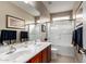 Bathroom featuring double sinks, cherry cabinets, large mirror and bathtub/shower combination with glass doors at 5622 W Cavedale Dr, Phoenix, AZ 85083