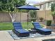 Relaxing poolside lounge chairs with a blue umbrella, set on a patterned rug, surrounded by lush greenery at 5622 W Cavedale Dr, Phoenix, AZ 85083