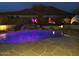 Evening shot of a backyard pool with a rock waterfall feature and landscape lighting at 6372 W Hill Ln, Glendale, AZ 85310