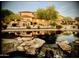 Pond reflecting townhomes, bushes, and rocks with small waterfalls at 7600 E Golden Eagle Cir, Gold Canyon, AZ 85118
