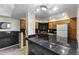 A well-equipped kitchen with a black countertop, wooden cabinets, and modern lighting fixtures at 8787 E Mountain View Rd # 2016, Scottsdale, AZ 85258