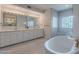 Bright bathroom featuring double vanities, elegant lighting, and a soaking tub with a glass-enclosed shower at 9041 N 46Th St, Phoenix, AZ 85028
