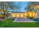 Exterior of home featuring grass lawn and paved driveway leading to an illuminated three-car garage at 9041 N 46Th St, Phoenix, AZ 85028