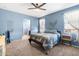 A bedroom with blue walls, carpeted floors, a ceiling fan, and access to a bathroom at 4053 N 308Th Ln, Buckeye, AZ 85396