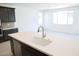 Modern kitchen showcasing a large white kitchen island with a stainless steel sink and dark wood cabinets at 2442 W Rowel Rd, Phoenix, AZ 85085