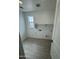 Well-lit laundry room with wood-look tile, utility sink hookups, and convenient shelf storage at 2470 W Rowel Rd, Phoenix, AZ 85085