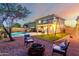 Serene backyard featuring a fire pit and swing set enhanced with landscape lighting for cozy outdoor enjoyment at 12229 N 121St Dr, El Mirage, AZ 85335