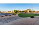 Community green space with paved street, dry creek bed, manicured lawn, mature trees, and flowering bushes at 12229 N 121St Dr, El Mirage, AZ 85335