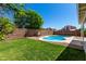 Private backyard oasis with a sparkling pool, lush lawn, and mature trees, perfect for outdoor enjoyment at 13711 N 81St Ave, Peoria, AZ 85381