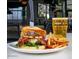 A gourmet burger stabbed with a knife served with fries and a glass of beer on a restaurant table at 1619 E Del Rio Dr, Tempe, AZ 85282