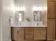 Double vanity bathroom with wood cabinets, two mirrors, and two sinks with modern fixtures at 17002 S 178Th Ave, Goodyear, AZ 85338