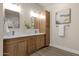 Bathroom featuring a double vanity with wood cabinets, two mirrors, and a white countertop at 17002 S 178Th Ave, Goodyear, AZ 85338