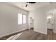 Bedroom with a ceiling fan, wood-look floors, and a doorway leading to a bathroom and closet at 17002 S 178Th Ave, Goodyear, AZ 85338