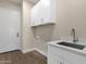 Well-lit laundry room with a white sink and white cabinets above the laundry hookups and a white entry door at 17002 S 178Th Ave, Goodyear, AZ 85338