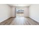 Bright, empty living room featuring wood-look flooring and sliding glass doors to the backyard at 17808 W Sanna St, Waddell, AZ 85355