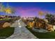 Enchanting backyard featuring illuminated stone steps, a rock waterfall, and manicured landscaping at twilight at 18116 N 14Th St, Phoenix, AZ 85022