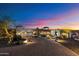 Striking front exterior view of a custom home with a circular driveway and desert landscaping at dusk at 18116 N 14Th St, Phoenix, AZ 85022