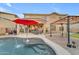 Resort-style backyard with a freeform pool, patio seating under an umbrella, and privacy landscaping at 18460 E Peachtree Blvd, Queen Creek, AZ 85142