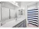 Well-lit bathroom showcasing a vanity with grey cabinets, a large mirror, and a tub with a blue-striped shower curtain at 2167 W Ethan Ct, San Tan Valley, AZ 85144