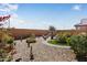 Landscaped backyard with decorative rock, winding pavers and lush plants, including a water fountain and artificial turf at 27391 W Wahalla Ln, Buckeye, AZ 85396