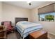 Cozy bedroom featuring a wood-frame bed with a blue quilt and natural light from a window at 27391 W Wahalla Ln, Buckeye, AZ 85396