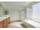 Bathroom featuring double sinks, wood cabinets, a tub, and glass door shower at 2982 E Boston St, Gilbert, AZ 85295