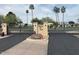 Gated entrance with a manicured lawn and mature palm trees at 3023 W Calavar Rd, Phoenix, AZ 85053