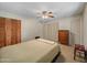 Comfortable bedroom with ceiling fan, wood dresser and closet doors for ample storage, with a cushioned stool at 3802 W Rue De Lamour Ave, Phoenix, AZ 85029