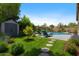 Landscaped backyard featuring a pool, lounge chairs, lush lawn, stepping stones, shed, and vibrant flowers at 384 N Scott Dr, Chandler, AZ 85225