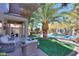Lush backyard with a sparkling pool, hammock, outdoor seating, and mature palm trees at 45176 W Alamendras St, Maricopa, AZ 85139