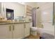 Bright bathroom featuring a granite vanity, a framed mirror and shower with a lavender colored curtain at 45176 W Alamendras St, Maricopa, AZ 85139
