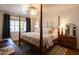 Cozy bedroom featuring a four-poster bed, ceiling fan, and natural light from a large window at 536 W Windsor Ave, Phoenix, AZ 85003