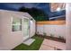 Cozy backyard featuring a small building with a window, a glass door, artificial grass, and a concrete seating area at 8215 E Virginia Ave, Scottsdale, AZ 85257