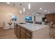 Kitchen island featuring a sink, brass faucet, and countertop with seating in an open floor plan at 8215 E Virginia Ave, Scottsdale, AZ 85257