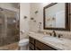 Well-lit bathroom featuring a glass shower, granite countertop, decorative wall plants, and a modern vanity mirror at 11224 E Carol Ave, Scottsdale, AZ 85259