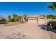 Beige home with a spacious three car garage, desert landscaping, and a long paver driveway at 11224 E Carol Ave, Scottsdale, AZ 85259