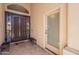An entryway featuring a dark wood door, sidelight, security screen door, and a sitting bench at 11224 E Carol Ave, Scottsdale, AZ 85259