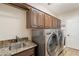 Laundry room equipped with granite counters, upper cabinets, and stainless-steel washer and dryer at 11224 E Carol Ave, Scottsdale, AZ 85259