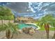 Backyard pool featuring rock waterfall feature and surrounded by mature landscaping at 15454 W Evans Dr, Surprise, AZ 85379