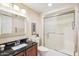 Cozy bathroom features a vanity with a black countertop and a walk-in shower with sliding glass doors at 17885 N 99Th Dr, Sun City, AZ 85373