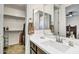 Bright bathroom featuring a white vanity, large mirror, and a view into a walk-in closet at 18120 W Cassia Way, Goodyear, AZ 85338